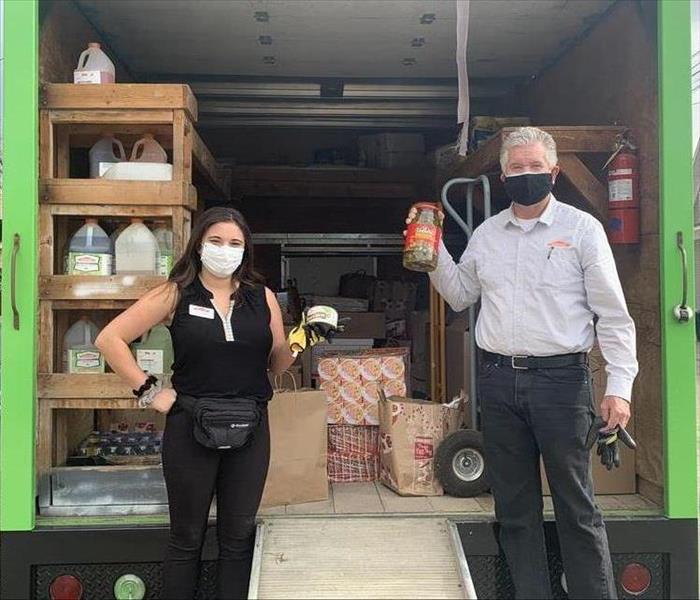 Woman and Man holding food in front of a green truck